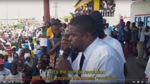 Caption: G9 Family and Allies leader Jimmy Cherizier speaks at a rally demanding an end to the Western puppet government of Haiti. Video source: Another Vision: Inside Haiti's Uprising | Episode 3: A Burgeoning Revolution, 28:02.