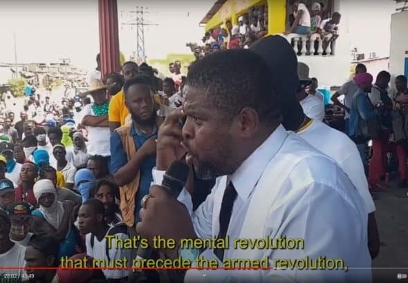 Caption: G9 Family and Allies leader Jimmy Cherizier speaks at a rally demanding an end to the Western puppet government of Haiti. Video source: Another Vision: Inside Haiti's Uprising | Episode 3: A Burgeoning Revolution, 28:02.
