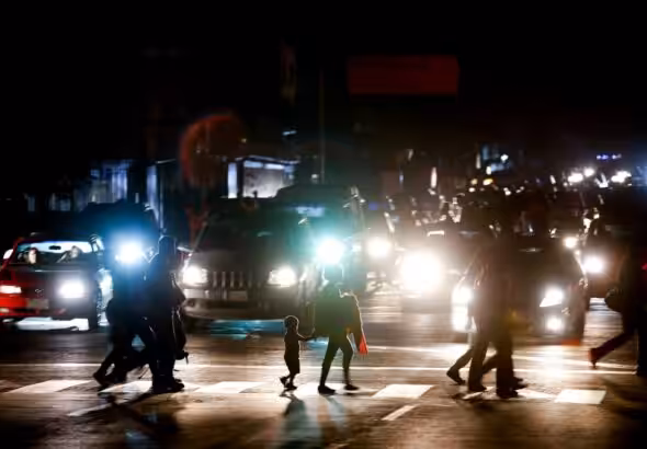 Residents cross a street during the power outage in Caracas, Venezuela. The act of sabotage left crowds of commuters in the capital city were walking home after metro service ground to a halt, and traffic snarled as motorists struggled to navigate intersections where traffic lights were out. Photo: Eduardo Verdugo/AP.