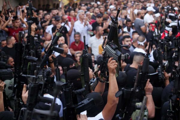 Members of the Palestinian resistance hold their weapons during a memorial service for Mohammed Al-Azizi and Abdul Rahman Sobh, who were killed by Israeli forces in July 2022, in the West Bank city of Nablus. Photo: Shadi Jarar’ah/APA images.