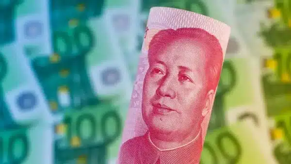 A banknote of China's 100 yuan with a portrait of Mao Zedong over a blurred background of euro banknotes. Photo: Gina Sanders/Fotolia via Wodicka.
