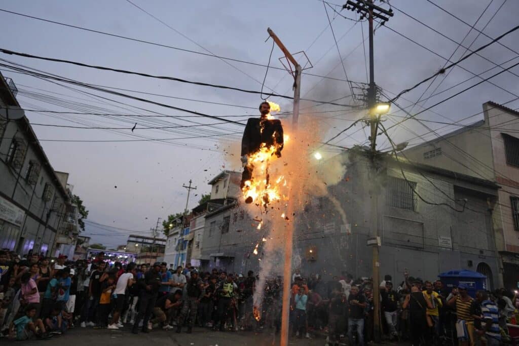 Residents burn a hanging "Judas" with a sign in Spanish that reads, "The Corrupt," in Caracas, Venezuela, April 9, 2023. Photo: AP/Ariana Cubillos.
