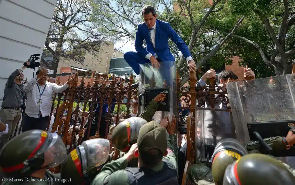 Former deputy Juan Guaidó tries to climb the fence to enter by the compound of Venezuela's National Assembly in Caracas, January 5, 2020. Photo: Matias Delacroix/AP Images.