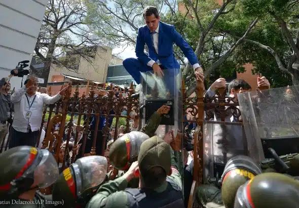 Former deputy Juan Guaidó tries to climb the fence to enter by  the compound of Venezuela's National Assembly in Caracas, January 5, 2020. Photo: Matias Delacroix/AP Images.
