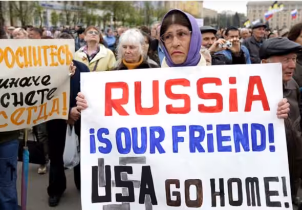 A woman holds a poster which reads \"Russia is our friends, USA do home\" during a pro-Russian rally in Kharkiv on April 21. Photo: Anastasia Vlasova.