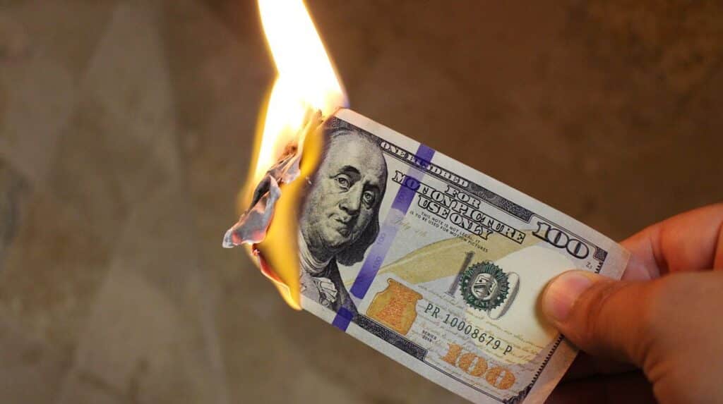One hundred dollars banknote being burned while hold by a person. Photo: chinausfocus.com.