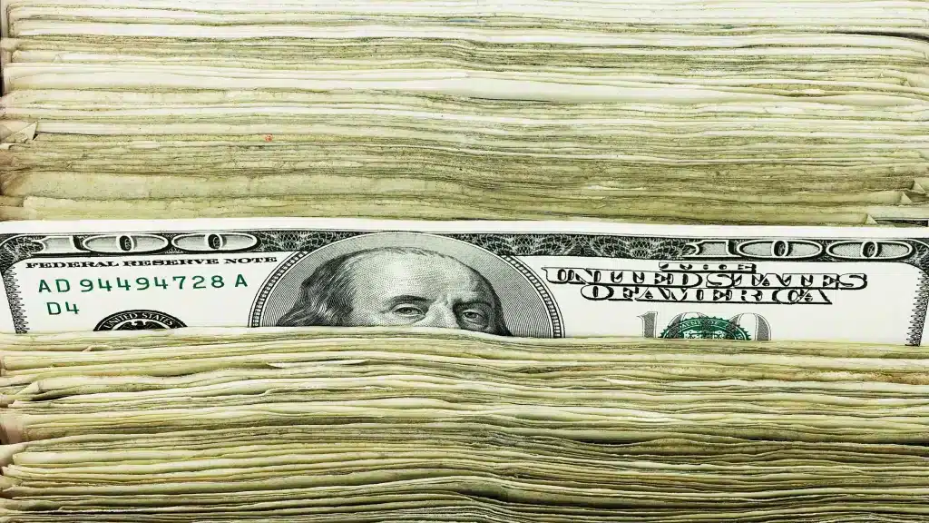 A stack of US dollars with a $100 bill peaking out. Photo: David Muir/Getty Images/File photo.