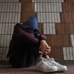 Child hunched over wearing a hoodie in front of a wall. Photograph: Gareth Fuller/PA Media.