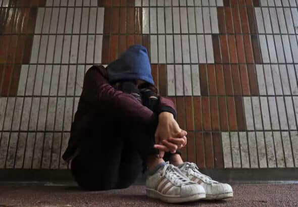 Child hunched over wearing a hoodie in front of a wall. Photograph: Gareth Fuller/PA Media.