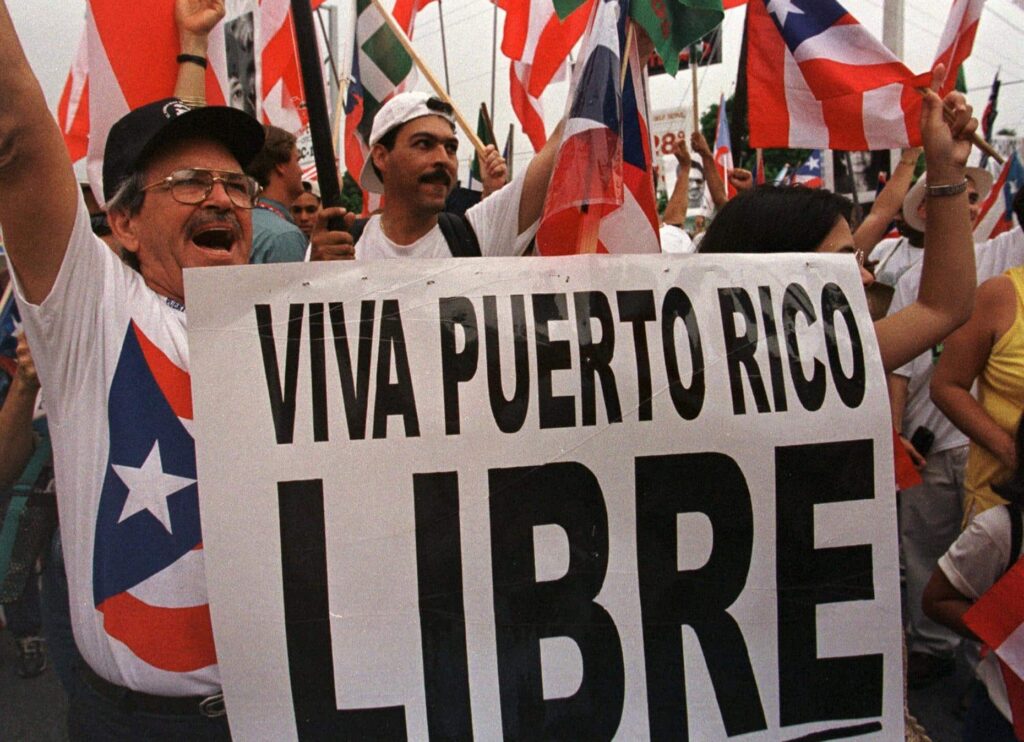People protesting with Puerto Rican flags and holding a banner that reads "Viva Puerto Rico Libre." Photo: AP/File photo.
