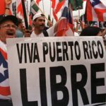 People protesting with Puerto Rican flags and holding a banner that reads "Viva Puerto Rico Libre." Photo: AP/File photo.