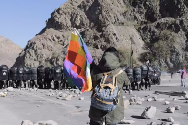 Protester holding a Wiphala flag faces a large group of riot police in Jujuy, Argentina. Photo: Susi Maresca.