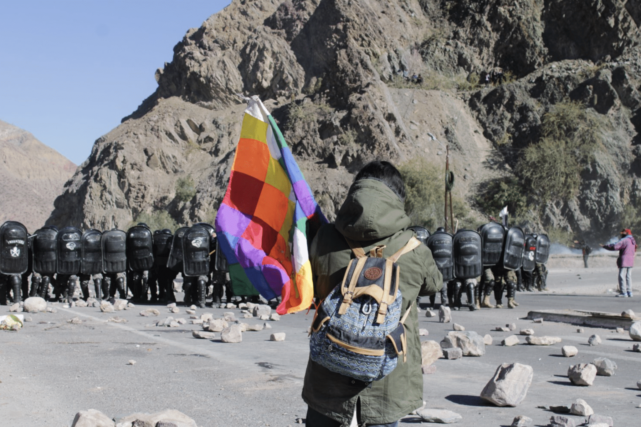 Protester holding a Wiphala flag faces a large group of riot police in Jujuy, Argentina. Photo: Susi Maresca.
