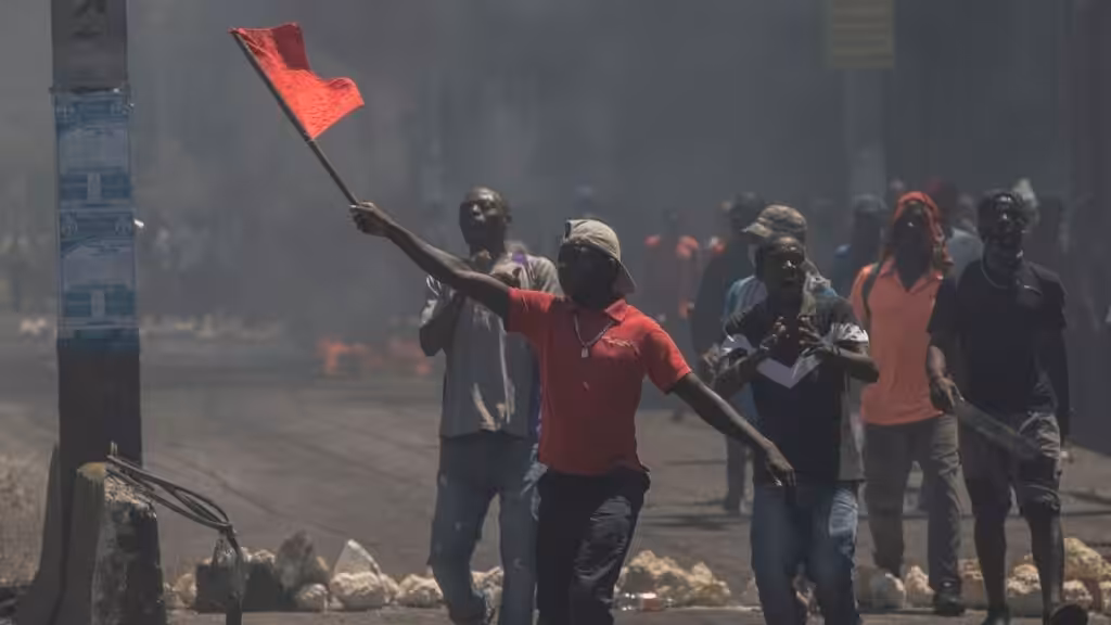 A man waves a red flag during a protest against fuel price hikes. Photo: AP/Odelyn Joseph.