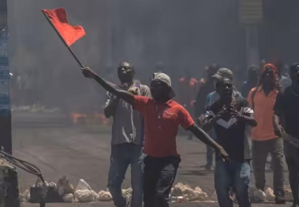 A man waves a red flag during a protest against fuel price hikes. Photo: AP/Odelyn Joseph.