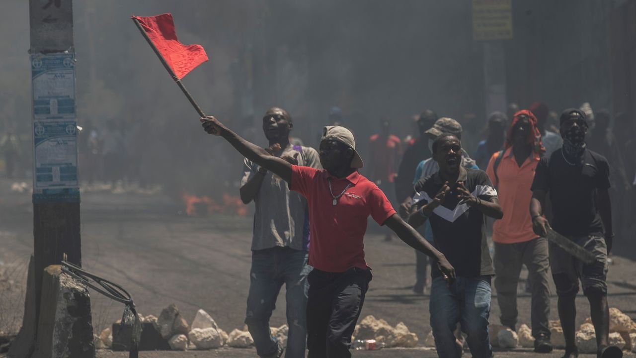 A man waves a red flag during a protest against fuel price hikes. Photo: AP/Odelyn Joseph.