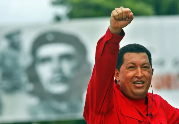 Venezuelan politician and revolutionary Bolivarian leader, Hugo Chávez, with his fist held high in the air, with a mural of Che Guevara in the background. Photo: Sven Creutzmann/Mambo photo/Getty Images/File photo.