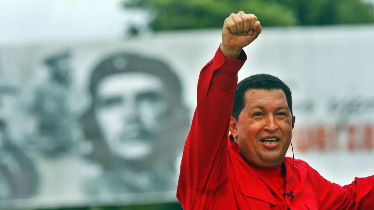 Venezuelan politician and revolutionary Bolivarian leader, Hugo Chávez, with his fist held high in the air, with a mural of Che Guevara in the background. Photo: Sven Creutzmann/Mambo photo/Getty Images/File photo.