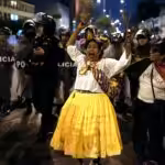 An opposition woman shouts in front of a police barricade during a march in downtown Lima, Peru, Wednesday, July 19, 2023. Protestors are demanding immediate early elections to Peruvian de facto ruler Dina Boluarte, as well as justice for those killed in the demonstrations that followed the parliamentary coup d'etat against President Castillo. Photo: AP/Rodrigo Abd.