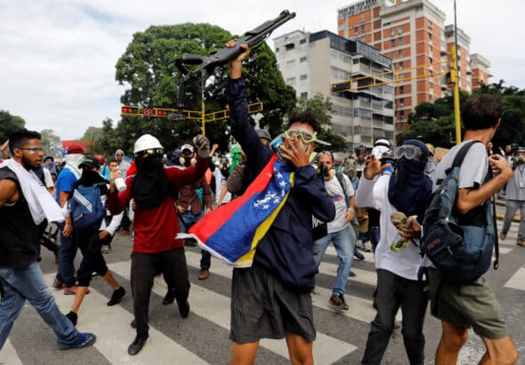 Opponents show a shotgun they snatched from police during a demonstration in Caracas, May 3, 2017. Photo: Carlos García Rawlins/Reuters.