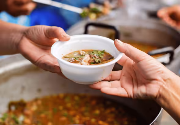 A person receiving a cup of soup in a street kitchen. Photo: File photo.