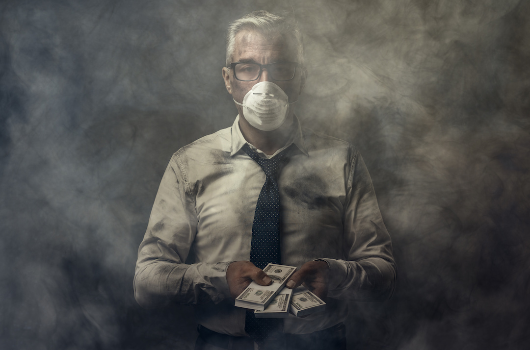 Business executive wearing a mask and holding cash banknotes. Photo: Getty Images.