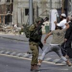 Soldiers of the apartheid state stand by as Zionist settlers throw stones at Palestinians during clashes in the town of Huwara in the West Bank on October 13, 2022. Photo: Oren Ziv/AFP.