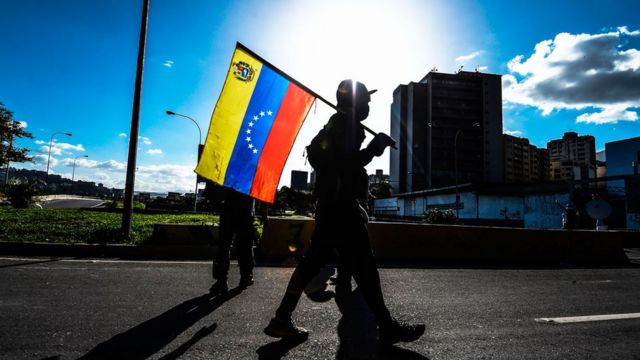 A PDVSA building and a Venezuelan flag. Photo: BBC.