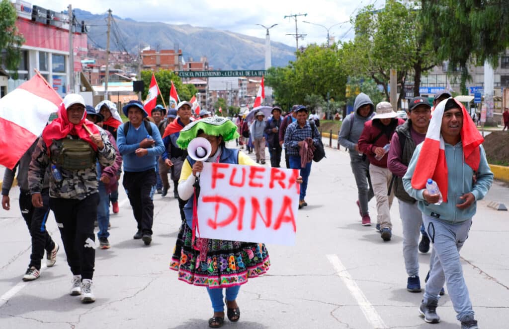 A demonstrator holds a placard that says "Out Dina" during a protest demanding Peru's Unelected "President" Dina Boluarte to step down and reinstate democratic processes, in Cuzco, Peru February 2, 2023. Photo: Paul Gambin/Reuters.