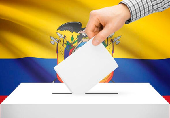A hand inserts a ballot into a ballot box, with the flag of Ecuador in the background. File photo.