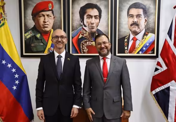 New UK head of diplomatic mission in Venezuela Colin Dick (left) next to Venezuelan Foreign Minister Yvan Gil (right), with portraits of Hugo Chávez, Simón Bolívar, and President Nicolás Maduro in the background, framed by the flags of both countries. Photo: X/yvangil.