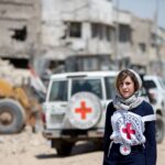 A Red Cross volunteer stands before a Red Cross vehicle in a disaster zone. Photo: Facebook/International Committee of the Red Cross.
