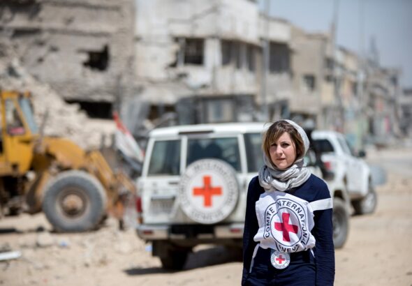 A Red Cross volunteer stands before a Red Cross vehicle in a disaster zone. Photo: Facebook/International Committee of the Red Cross.