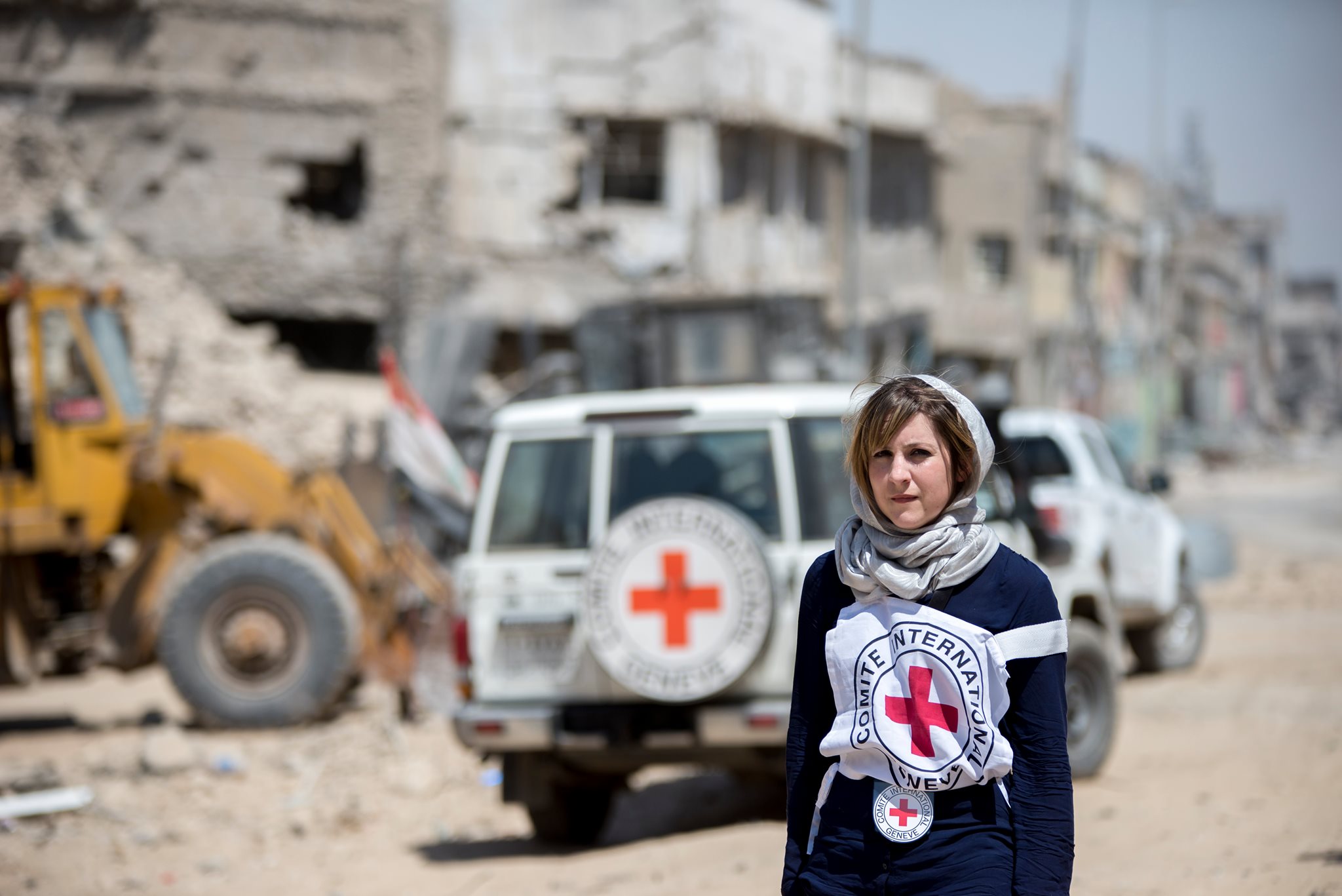 A Red Cross volunteer stands before a Red Cross vehicle in a disaster zone. Photo: Facebook/International Committee of the Red Cross.