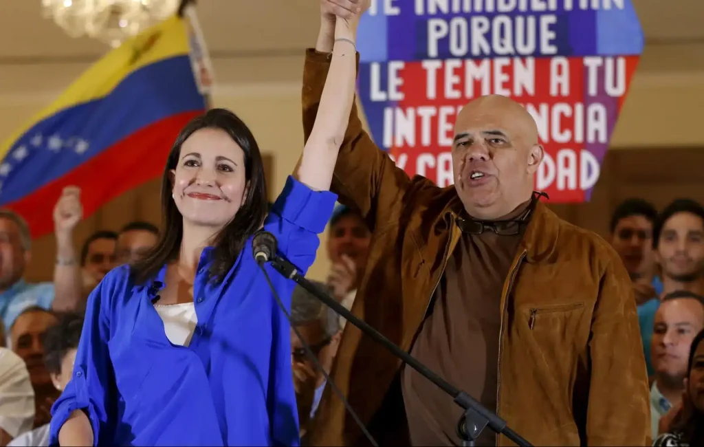 Opposition figure JesĂşs "Chuo" Torrealba (right) raising the hand of far-right politician Maria Corina Machado (left) and during a MUD event in 2015. Photo: Carlos Garcia Rawlings/Reuters/File photo.