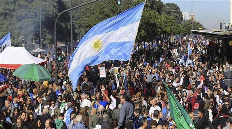 Argentinian demonstrators hold up a flag of Argentina amidst a large crowd of fellow demonstrators. Photo: Prensa Latina.