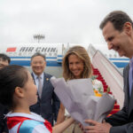 A handout picture released by the official Syrian Arab News Agency (SANA) shows Syria's President Bashar al-Assad (R) and First Lady Asma al-Assad (2-R) being welcomed upon their arrival at the airport in Beijing, on September 21, 2023. Photo: AFP.