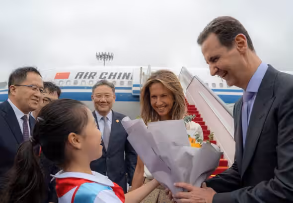 A handout picture released by the official Syrian Arab News Agency (SANA) shows Syria's President Bashar al-Assad (R) and First Lady Asma al-Assad (2-R) being welcomed upon their arrival at the airport in Beijing, on September 21, 2023. Photo: AFP.