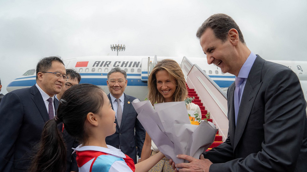 A handout picture released by the official Syrian Arab News Agency (SANA) shows Syria's President Bashar al-Assad (R) and First Lady Asma al-Assad (2-R) being welcomed upon their arrival at the airport in Beijing, on September 21, 2023. Photo: AFP.