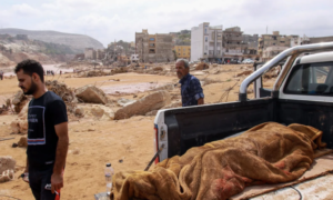 People walk past the body of a flash flood victim in Derna, eastern Libya, on September 11, 2023. Photo: AFP.