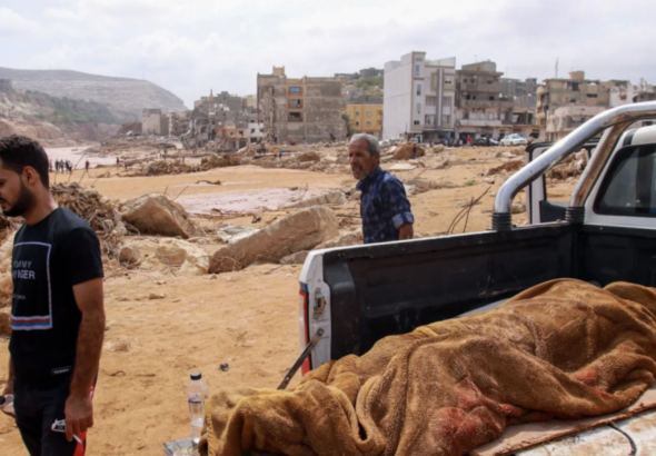 People walk past the body of a flash flood victim in Derna, eastern Libya, on September 11, 2023. Photo: AFP.