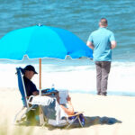 US President Joe Biden (left) and First Lady Jill Biden sit under an umbrella with a secret service agent nearby, in Rehoboth Beach, Delaware, on August 1, 2023. Photo: AFP.