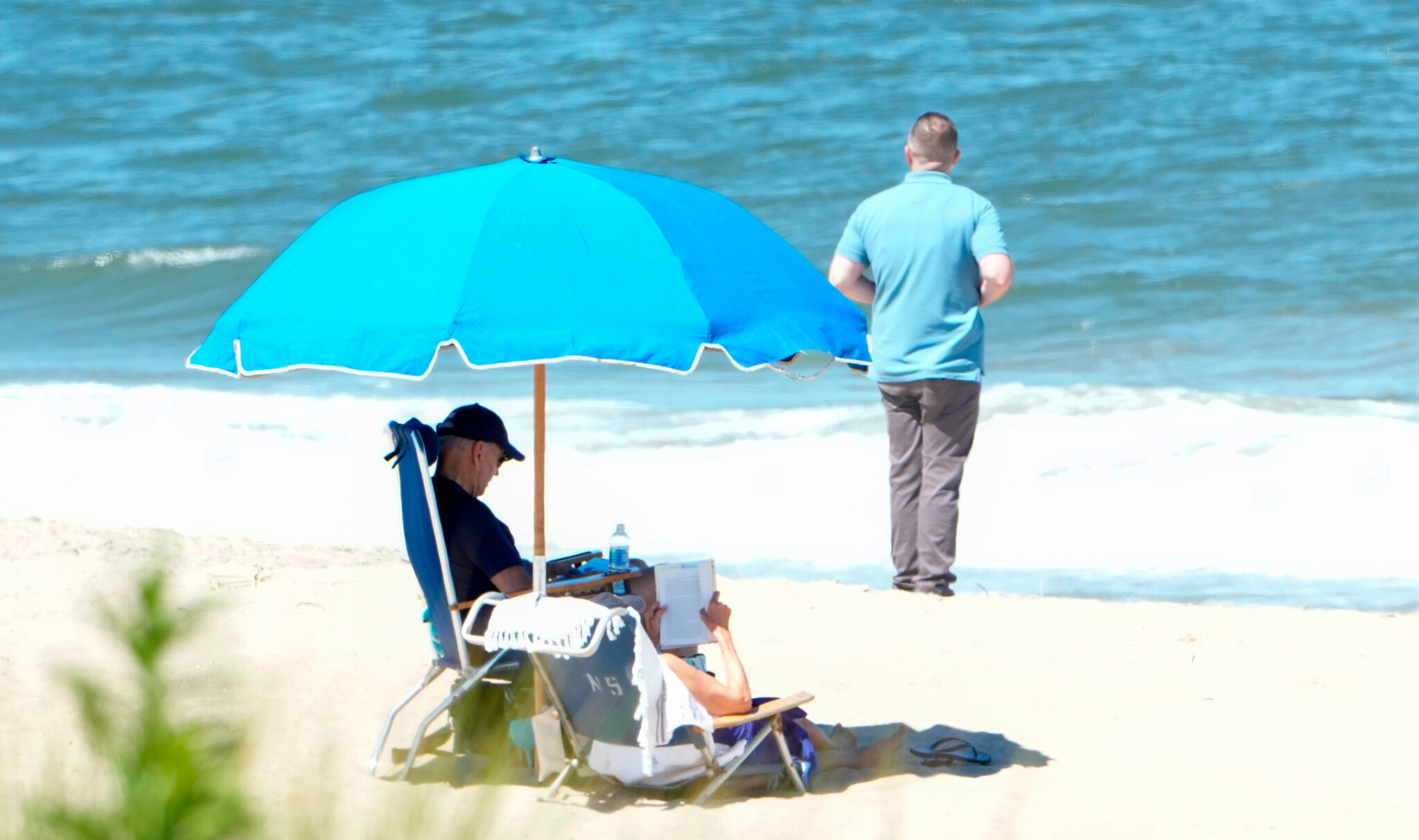 US President Joe Biden (left) and First Lady Jill Biden sit under an umbrella with a secret service agent nearby, in Rehoboth Beach, Delaware, on August 1, 2023. Photo: AFP.