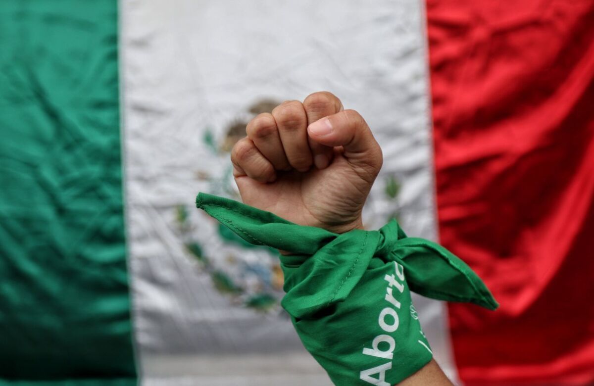 A fist raised high in resistance with a fabric wrapped around the wrist, captioned "aborto" (abortion), in front of a Mexican flag. Photo: Expansion Politica/File photo.
