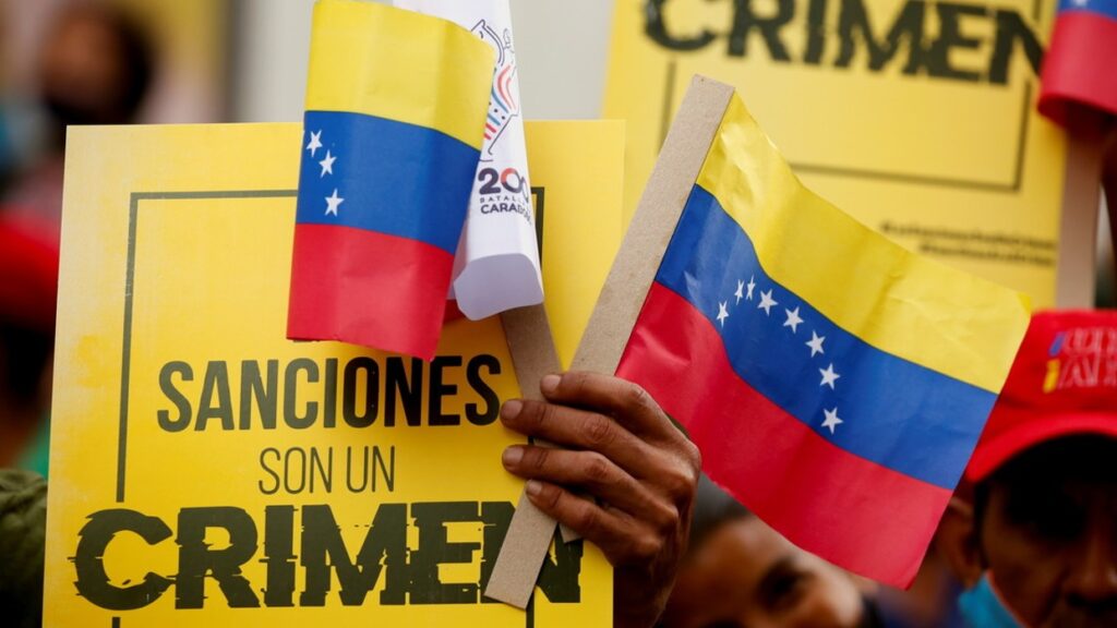 Venezuelans marching, holding a banner saying "Sanctions Are A Crime." Photo: File photo.