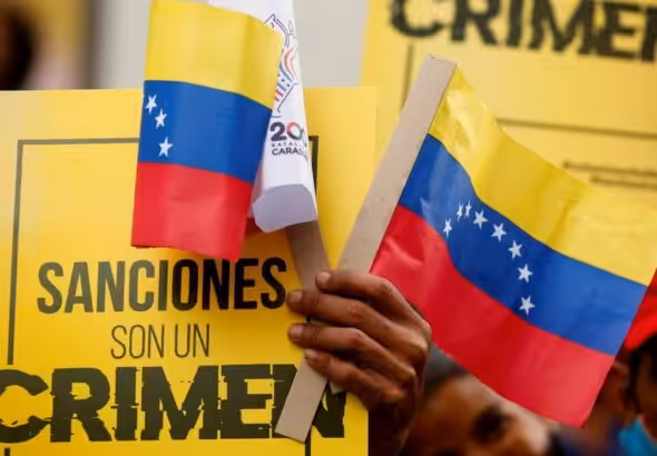 Venezuelans marching, holding a banner saying "Sanctions Are A Crime." Photo: File photo.