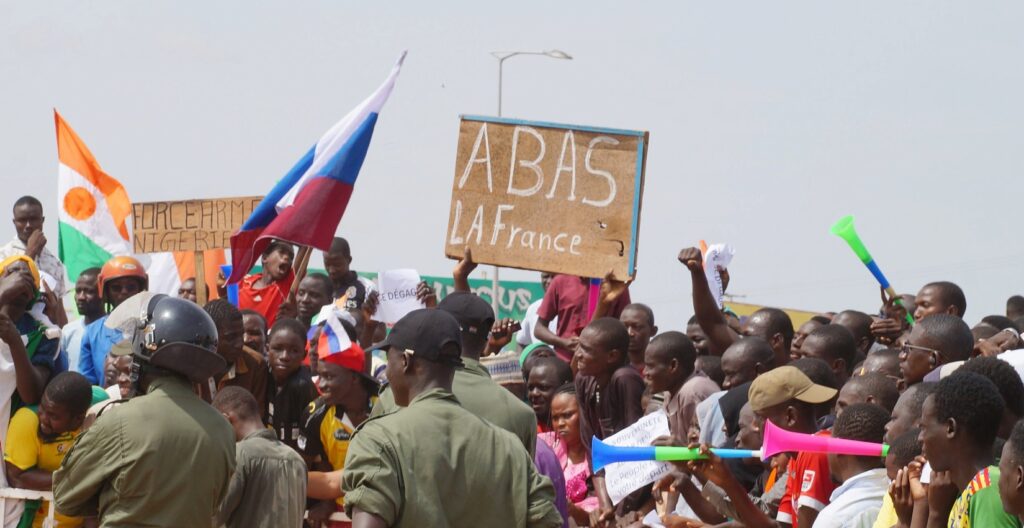 Protesters in Niger demand withdrawal of French troops while holing a Russian flag and a banner that reads down with France.  Photo: Balima Boureima/Anadolu via Getty.