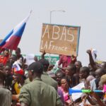 Protesters in Niger demand withdrawal of French troops while holing a Russian flag and a banner that reads down with France.  Photo: Balima Boureima/Anadolu via Getty.