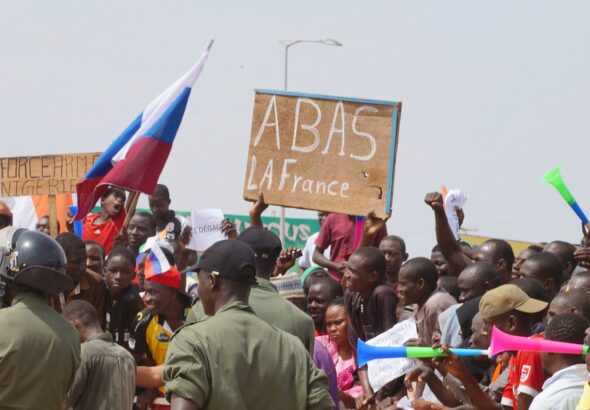Protesters in Niger demand withdrawal of French troops while holing a Russian flag and a banner that reads down with France.  Photo: Balima Boureima/Anadolu via Getty.