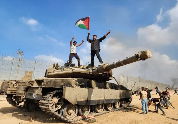 Hamas’ armed wing, the Izz ad-Din al-Qassam Brigades hold a Palestinian flag as they destroy a tank of Israeli forces in Gaza City, Gaza on October 07, 2023. Photo: Hani Alshaer – Anadolu Agency.